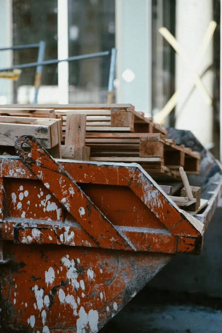 Steel debris container loaded with wood pallets at a construction site